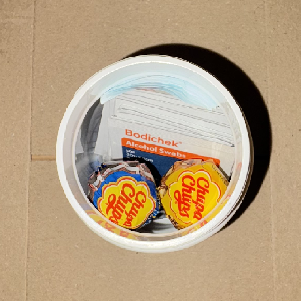 Two Chupa Chups lollipops placed on top of the alcohol swabs inside the capsule tub.